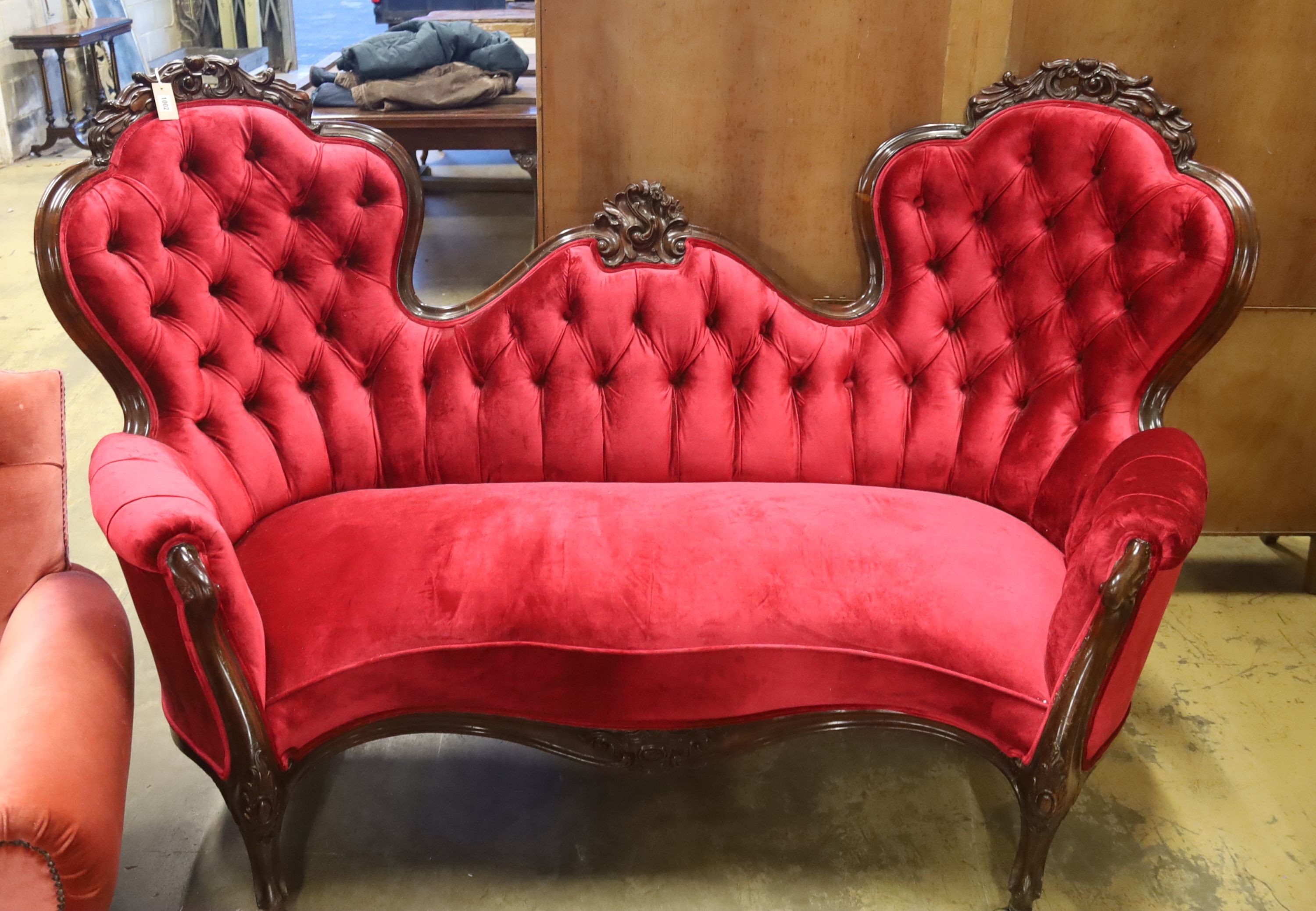 A Victorian carved rosewood double spoon back settee upholstered in deep buttoned scarlet velvet, length 200cm, depth 96cm, height 122cm